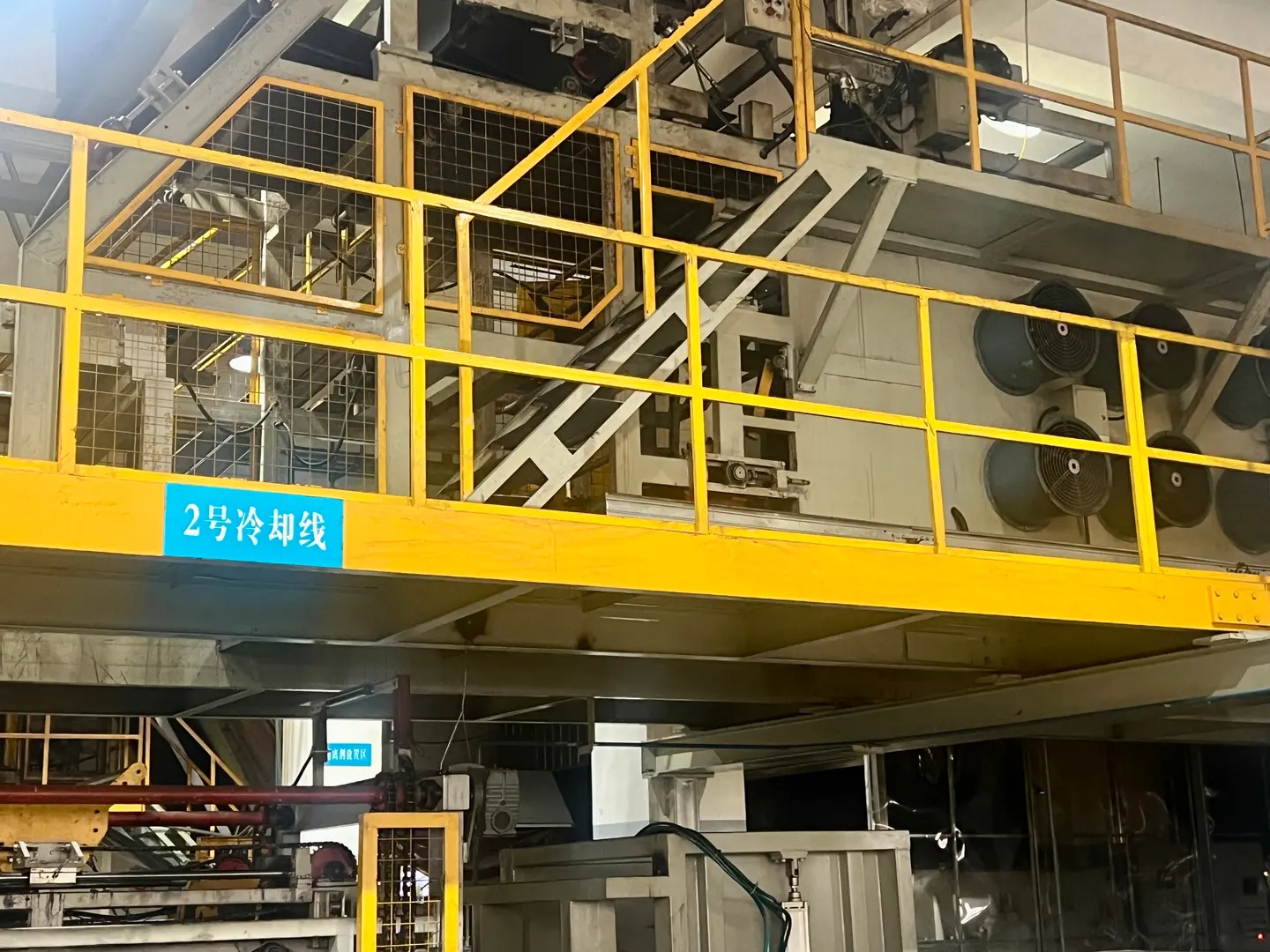 Workshop equipment carrying a cooling-line sign beside a yellow-railed platform