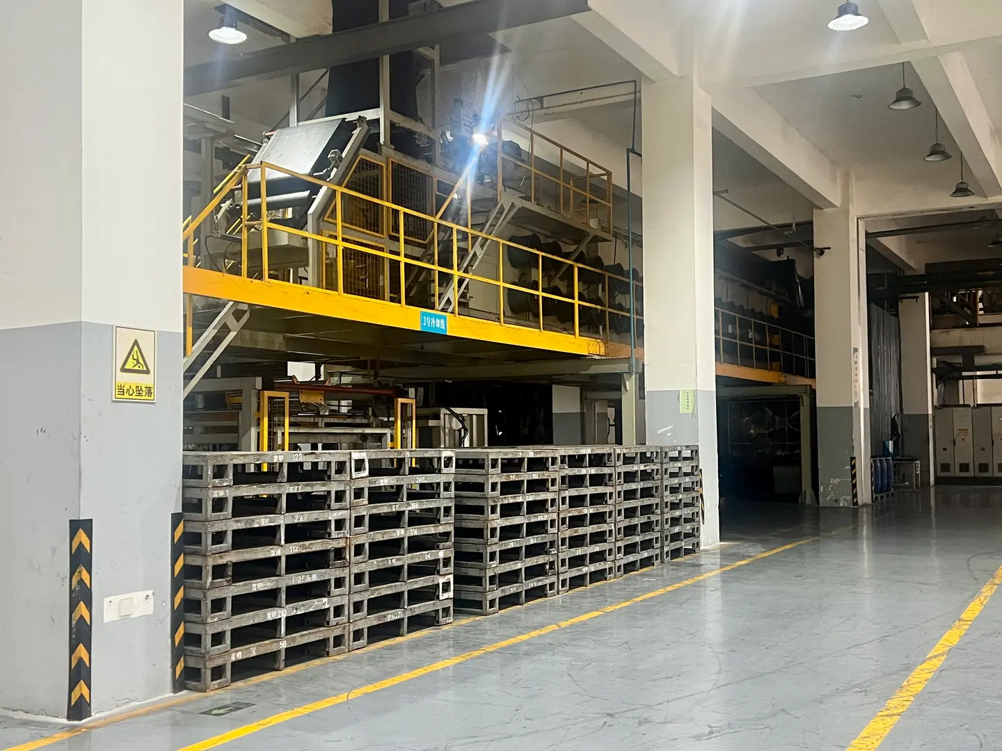 Workshop processing equipment behind a yellow-railed platform